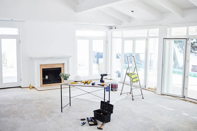 A bright, unfinished room with a fireplace, tools on a table