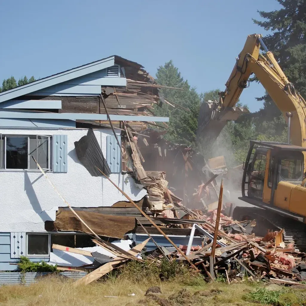 A bulldozer demolishes a partially collapsed house A bulldozer demolishes a partially collapsed house