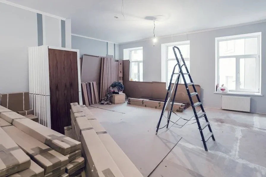A partially furnished, light-filled room under renovation