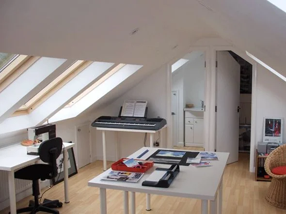 Bright attic room with desk keyboard and natural light Bright attic room with desk, keyboard, and natural light