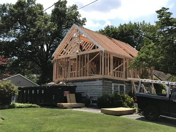 House under construction with wooden framing and dumpster