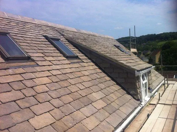 Roof with slates, skylights, and a view of hills