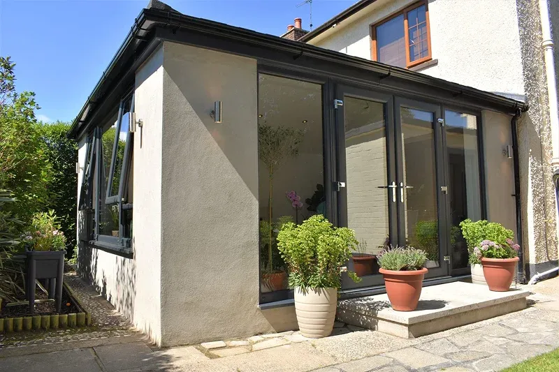 glass extension with potted plants and stone pathway